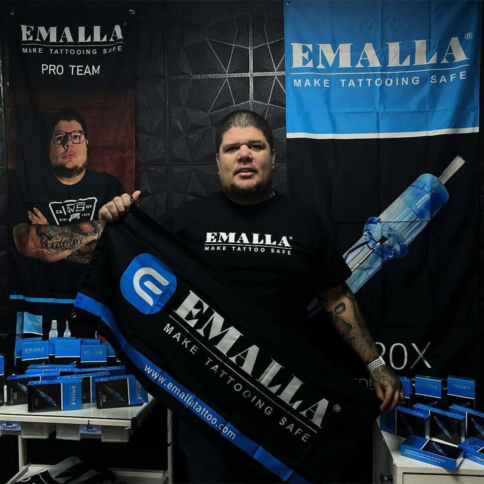 Emalla proteam artist Andres Jaime stand holds Emalla banner MAKE TATTOOING SAFE by Emalla exhibition booth