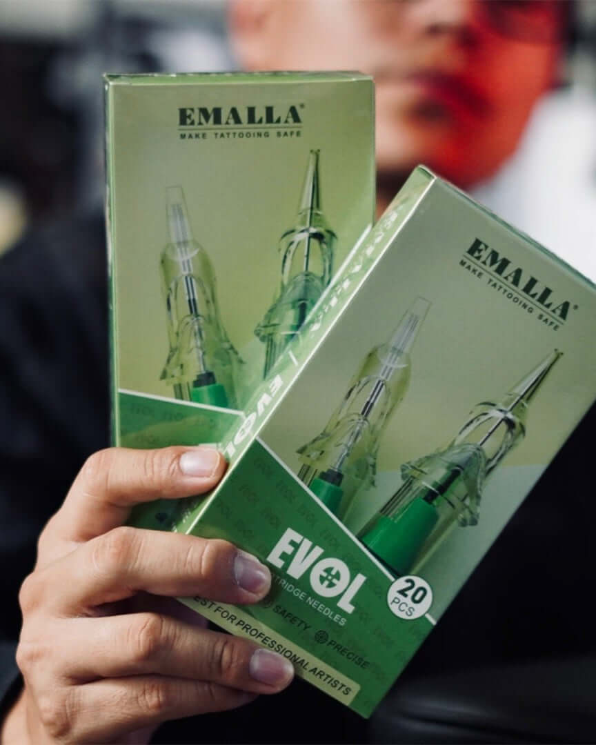 EMALLA EVOL tattoo cartridge needles box held by a tattoo artist, professional tattoo needle cartridges for precise tattooing